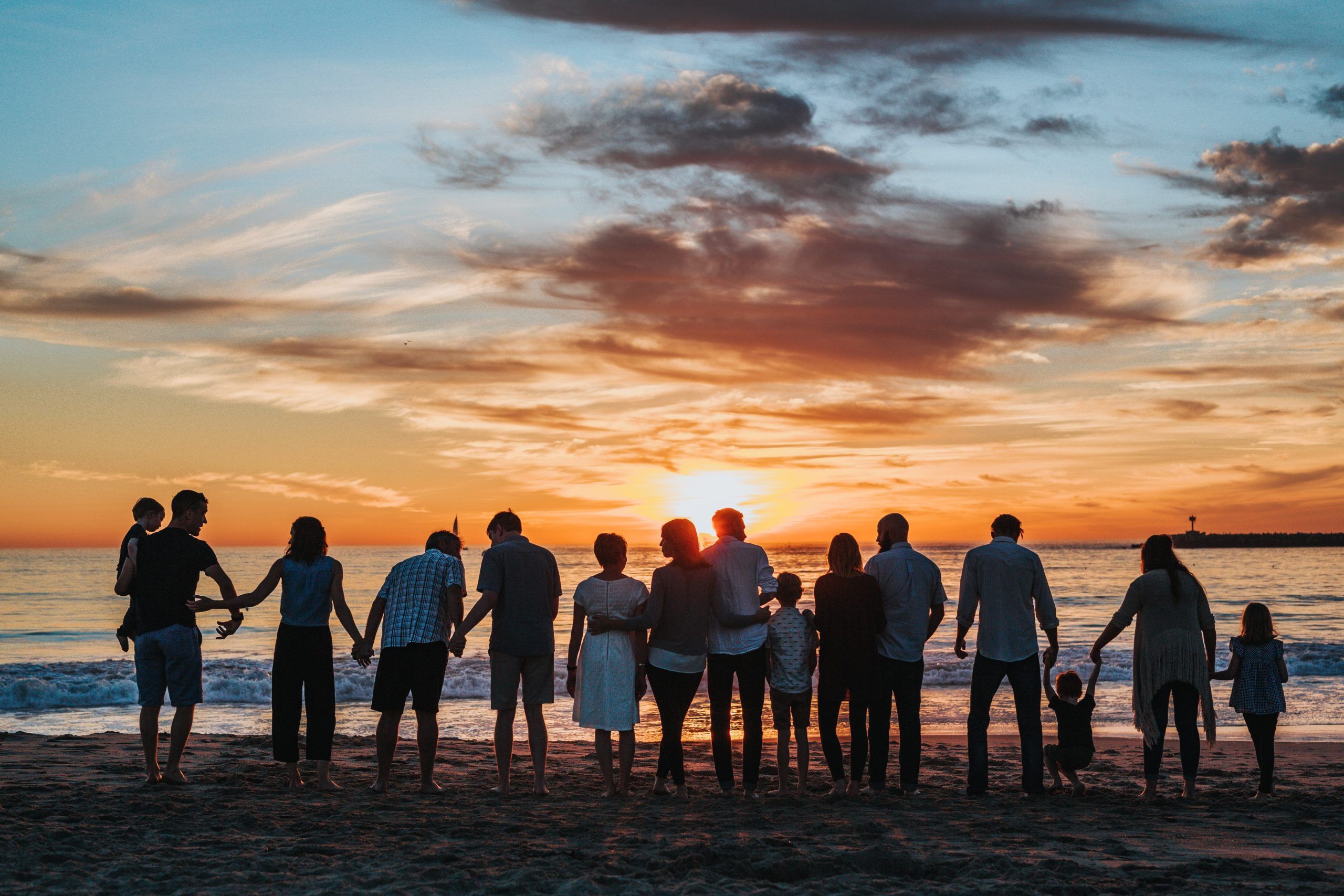 group of people holding hands on the beach with sunset